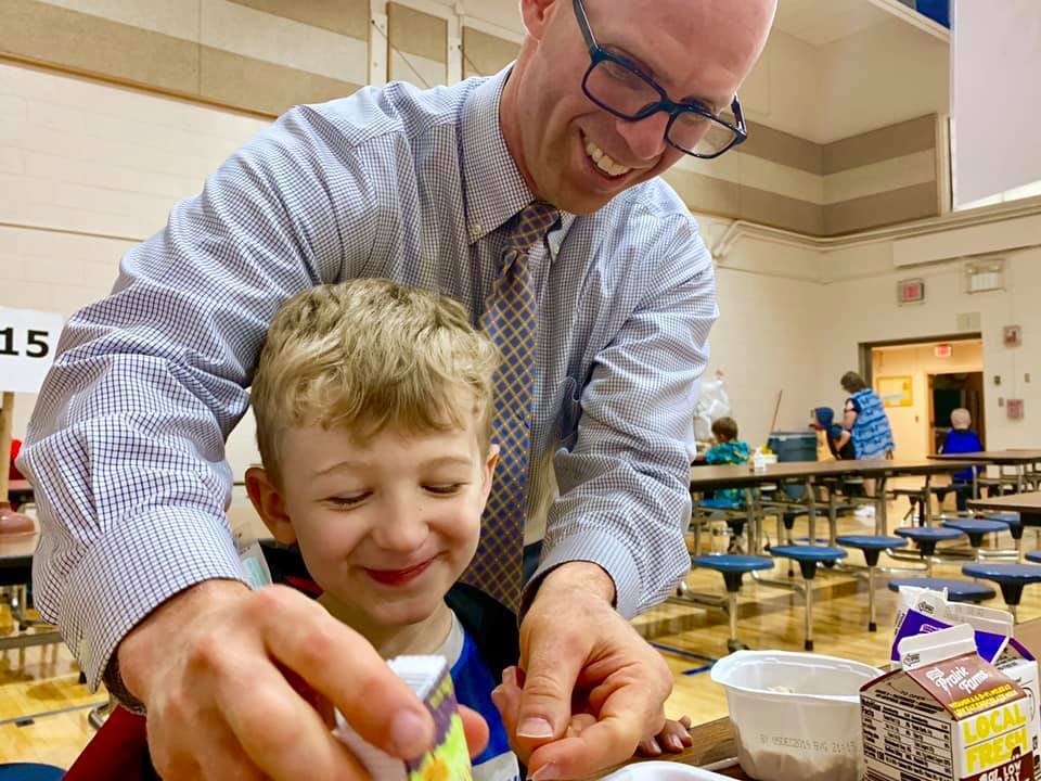Superintendent Tom Livezey helping an elementary student open a juice box